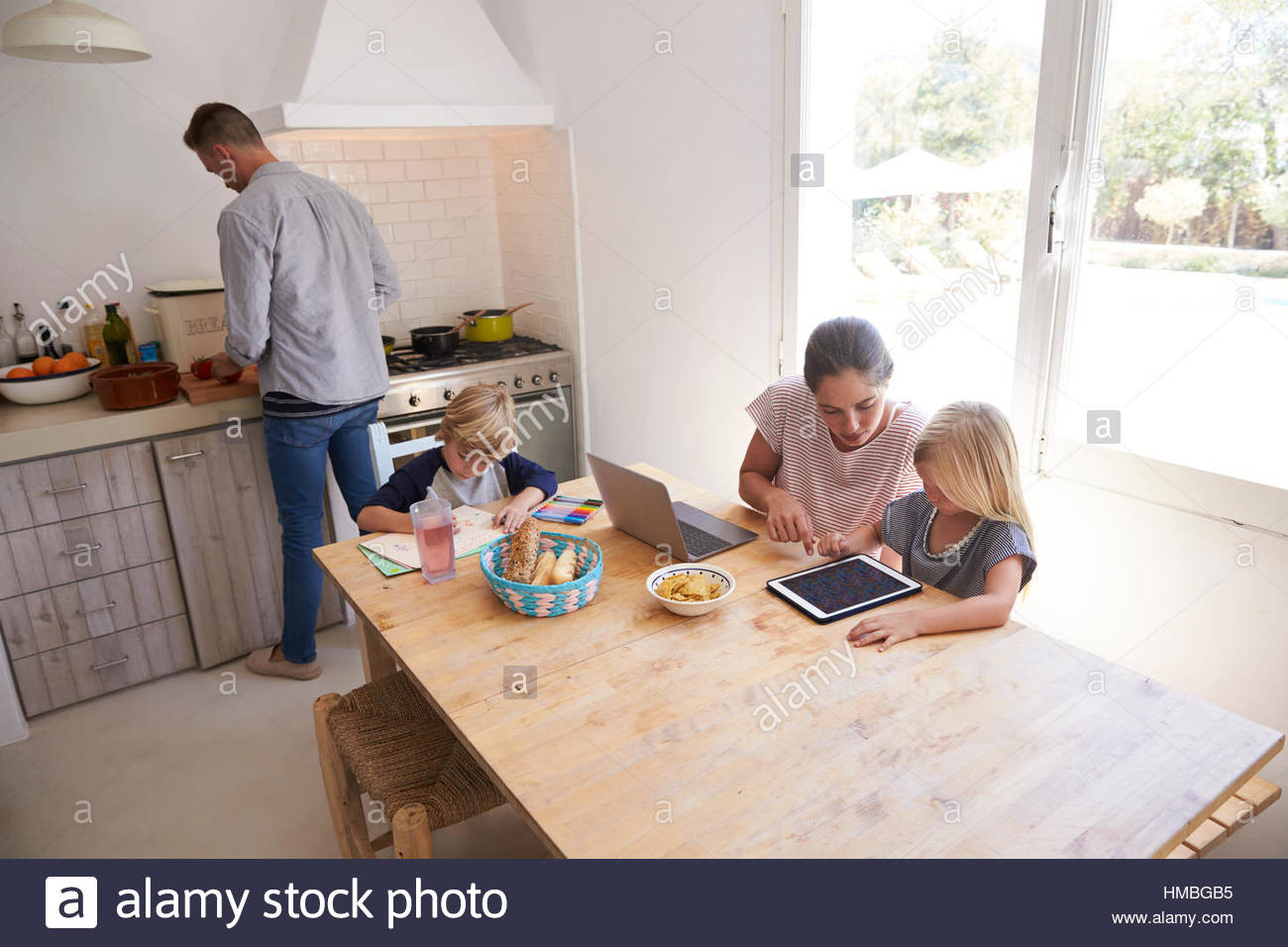 Kids Kitchen Table
 Dad cooking and mum with kids at kitchen table high angle