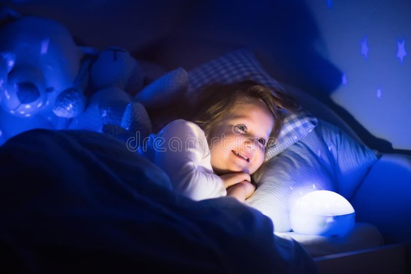 Kids Room Night Light
 Little Girl Reading A Book In Bed Stock Image